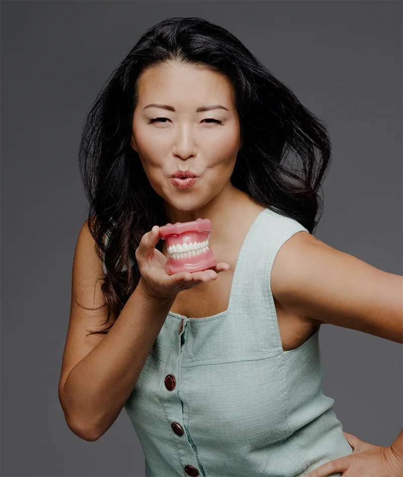 Dentist Dr. Grace Blowing a Kiss While Holding Teeth Model