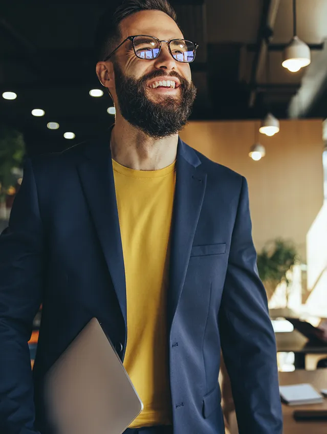 Entrepreneur In Office With Laptop Smiling
