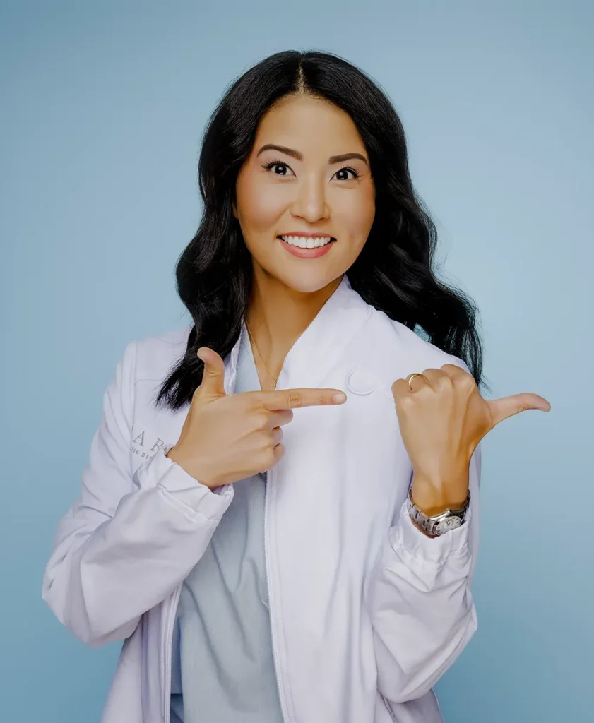 Dr. Grace Jun, DDS Smiling & Pointing At HARA Cosmetic Dentistry